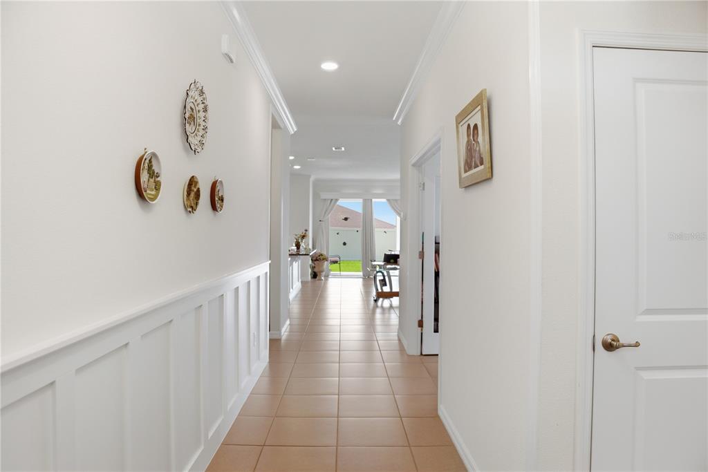 A tiled hallway leads past white wainscoting and wall decor toward a bright living area — 9152 SW 60TH COURT ROAD, OCALA, FL