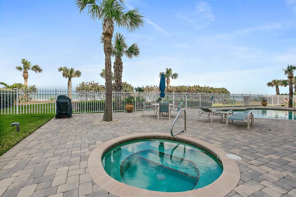 A circular hot tub sits on a paved patio next to a swimming pool — 711 S ATLANTIC AVENUE Unit 202, NEW SMYRNA BEACH, FL