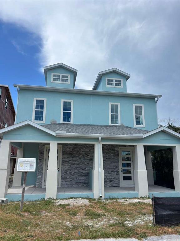 A two-story light blue duplex with a stone facade, covered front porches, and two dormers — 6177 1ST AVENUE N, ST PETERSBURG, FL