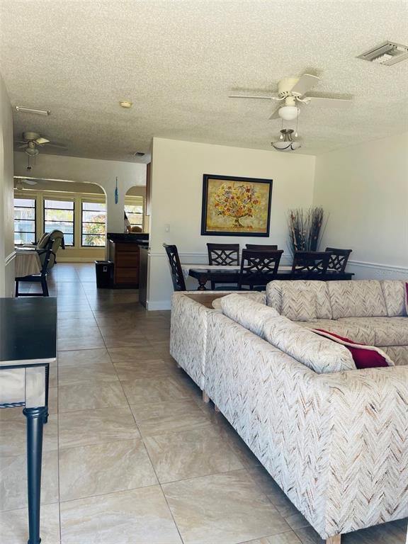A living room with tile floors, a sectional sofa, and an adjacent dining area — 18310 BURKHOLDER CIRCLE, PORT CHARLOTTE, FL