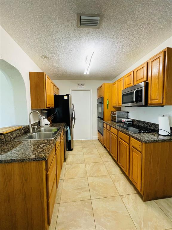 A galley kitchen features oak cabinets, granite countertops, stainless steel appliances, and tile flooring — 18310 BURKHOLDER CIRCLE, PORT CHARLOTTE, FL