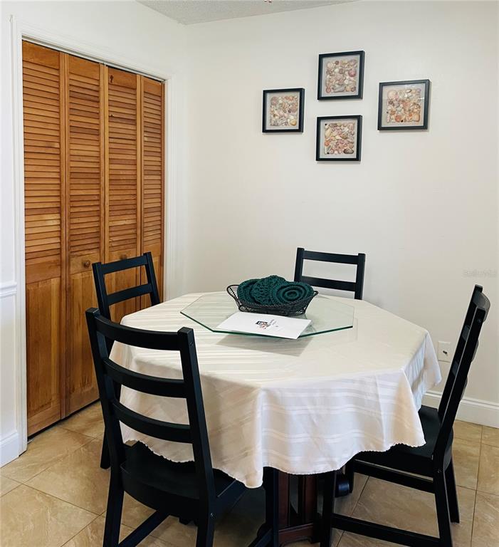 A dining area features a round table with four black chairs and wall-mounted shell art — 18310 BURKHOLDER CIRCLE, PORT CHARLOTTE, FL