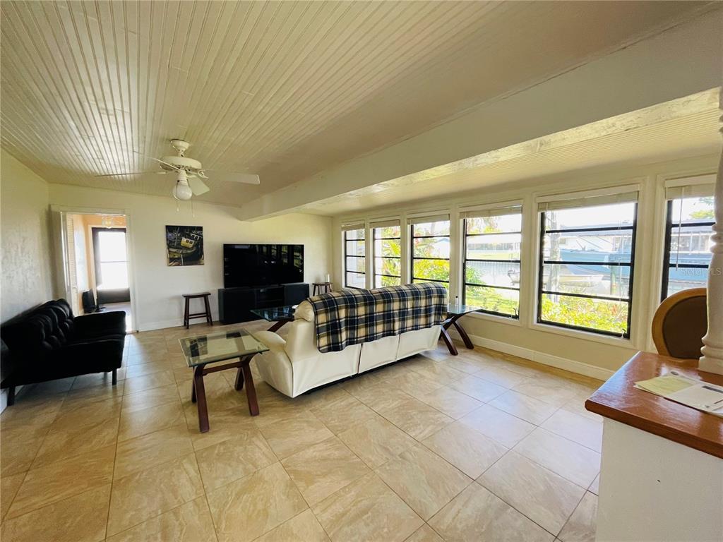 A living room with tile floors, a white sofa, and large windows overlooking a canal — 18310 BURKHOLDER CIRCLE, PORT CHARLOTTE, FL