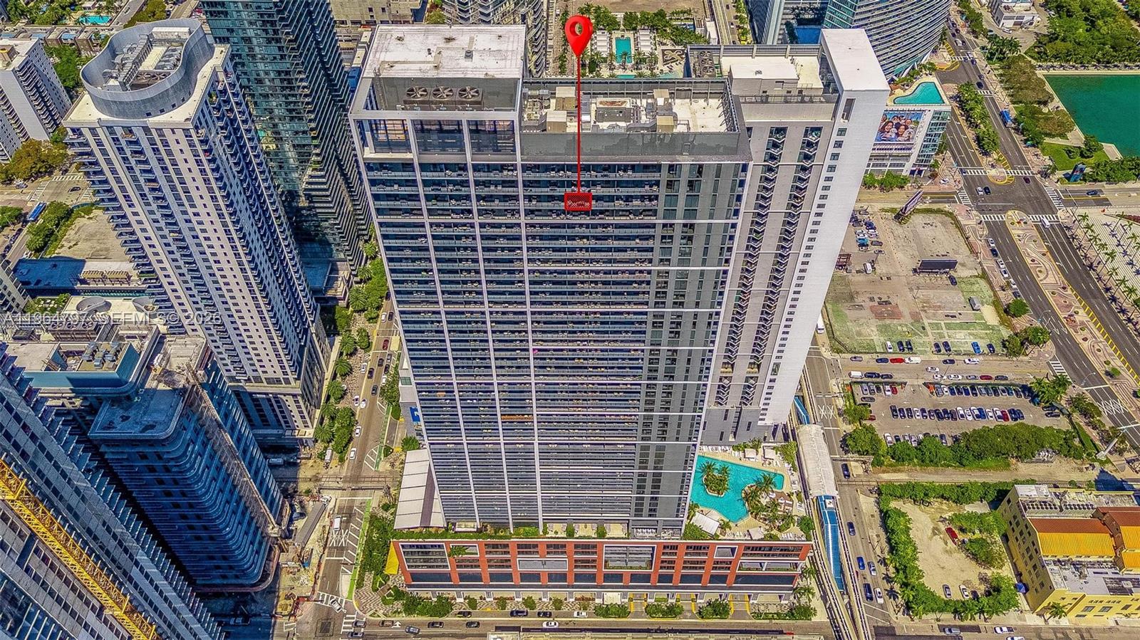 An aerial view shows a tall modern apartment building with a red location marker — 159 NE 6th St # 4910, Miami FL 33132, MIAMI, FL