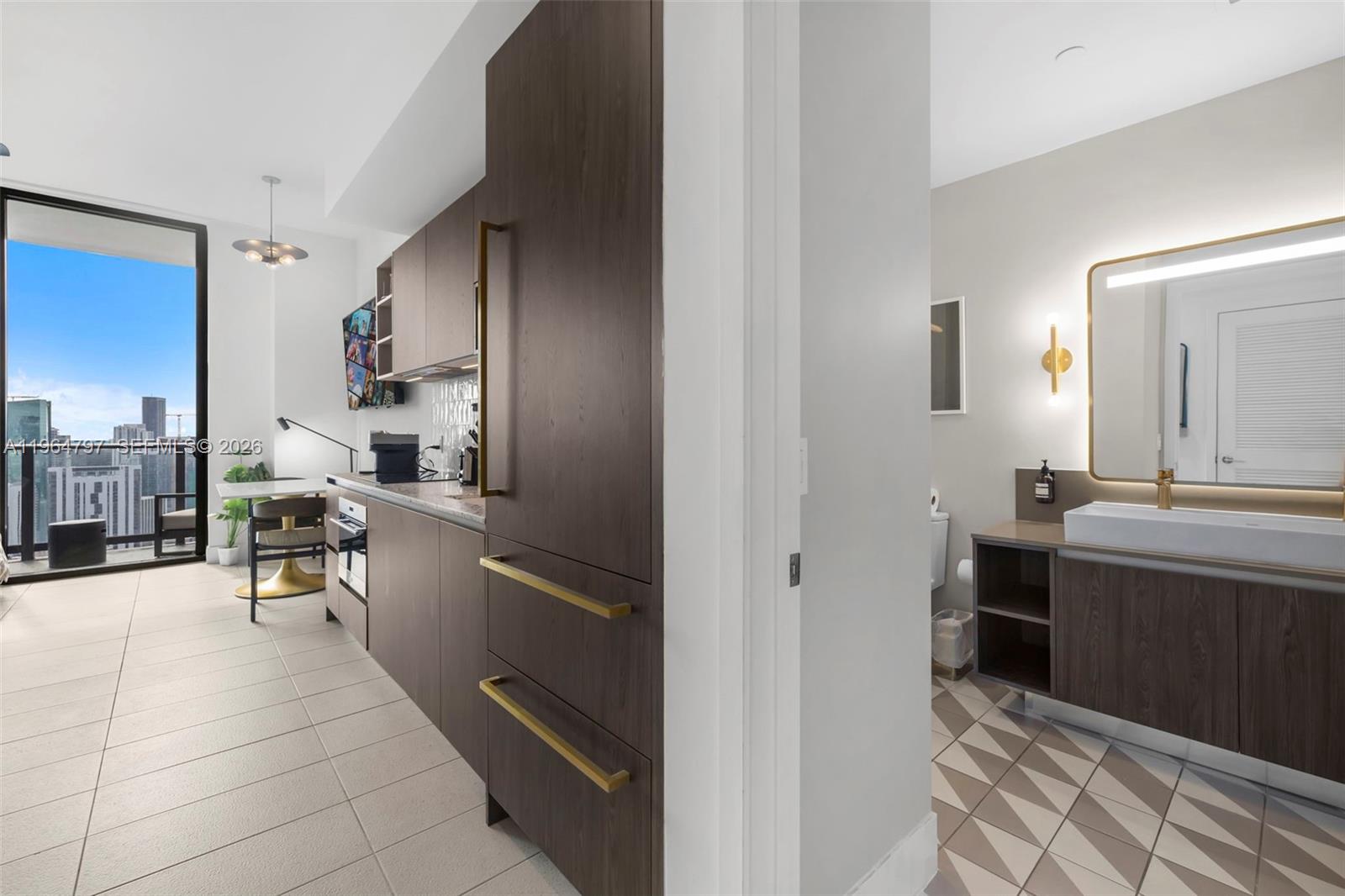 A modern kitchen with dark wood cabinetry and a bathroom with patterned floor tiles — 159 NE 6th St # 4910, Miami FL 33132, MIAMI, FL