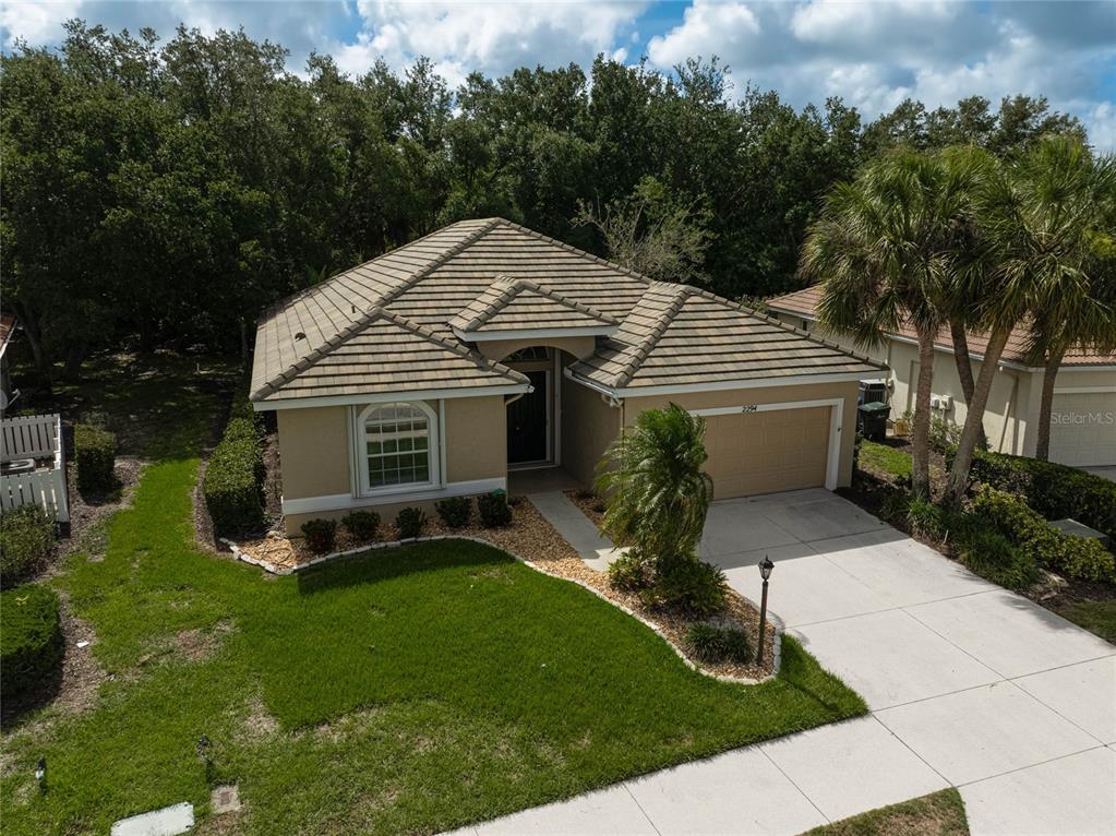 An aerial view shows a single-story house with a tan exterior, tile roof, and garage — 2294 HARRIER WAY, NOKOMIS, FL
