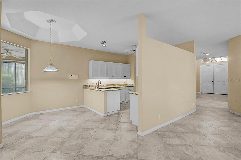 A kitchen with white cabinets and a breakfast bar opens to a tiled dining area — 2294 HARRIER WAY, NOKOMIS, FL