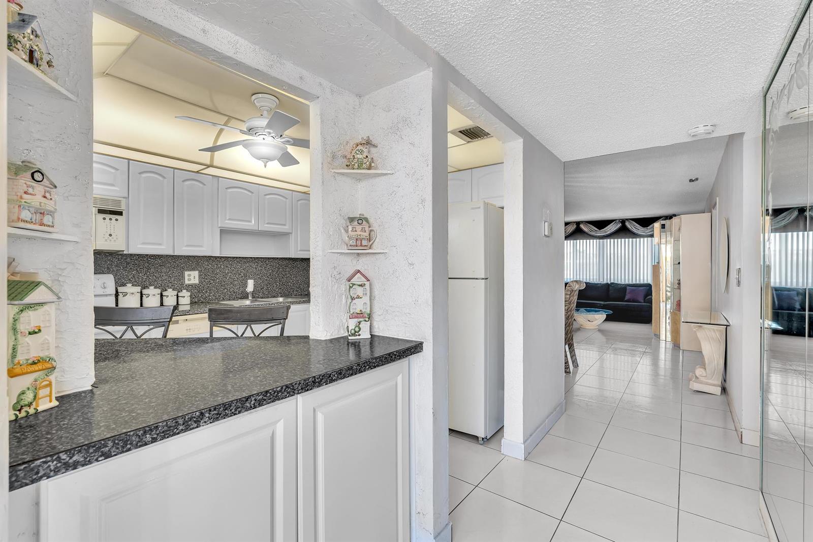 A view from a kitchen counter looking toward a hallway and a living room — 6670 Royal Palm Boulevard # 110, Margate FL 33063, MARGATE, FL