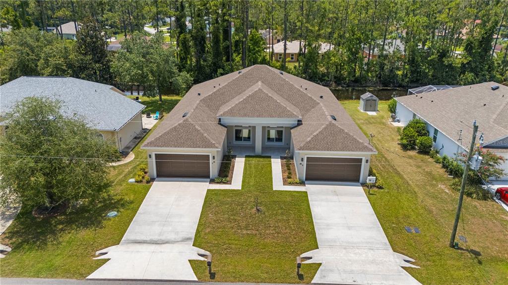 An aerial view of a duplex house with two garages and a shared lawn — 86 EMERSON DRIVE, PALM COAST, FL