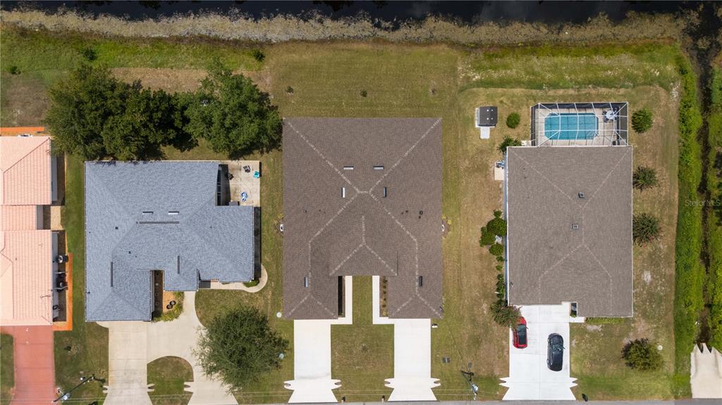 An aerial view shows three suburban houses with driveways, roofs, and a backyard swimming pool — 86 EMERSON DRIVE, PALM COAST, FL