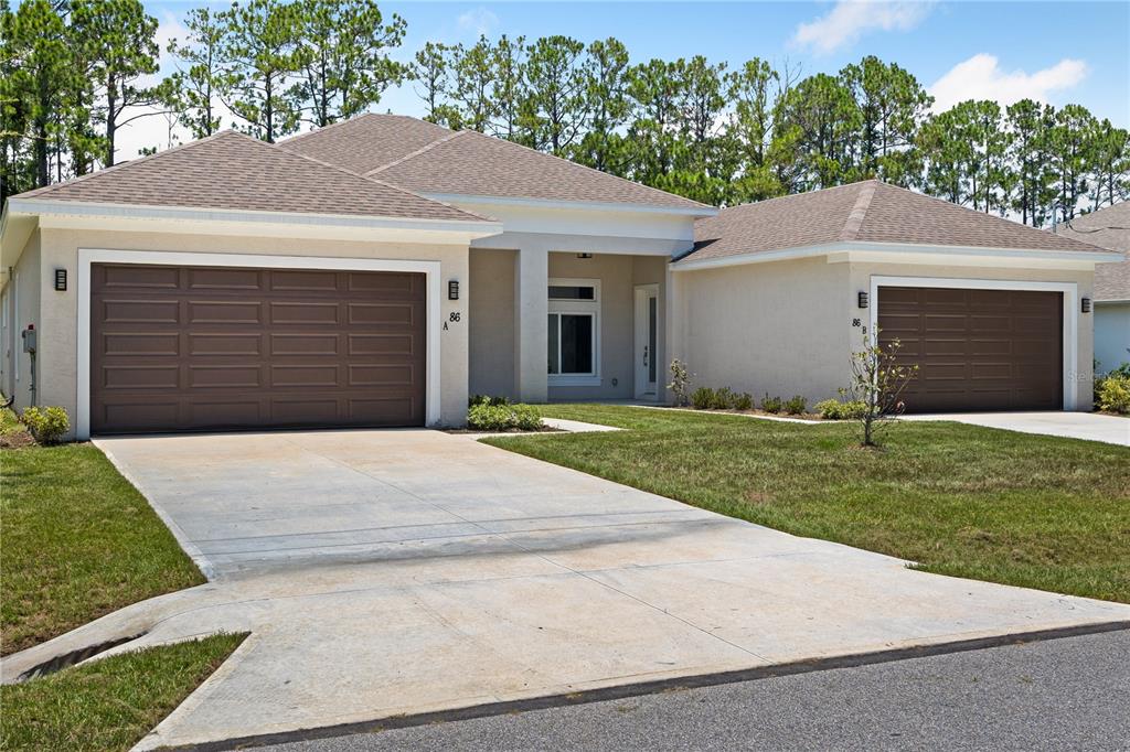 A duplex house with two brown garage doors and a central entryway under a roof — 86 EMERSON DRIVE, PALM COAST, FL