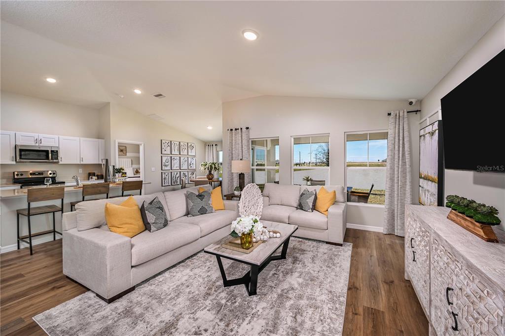 A living room features a light-colored sofa, a coffee table, and an open-concept kitchen — 4184 RIVER BEACON BOULEVARD, DAVENPORT, FL