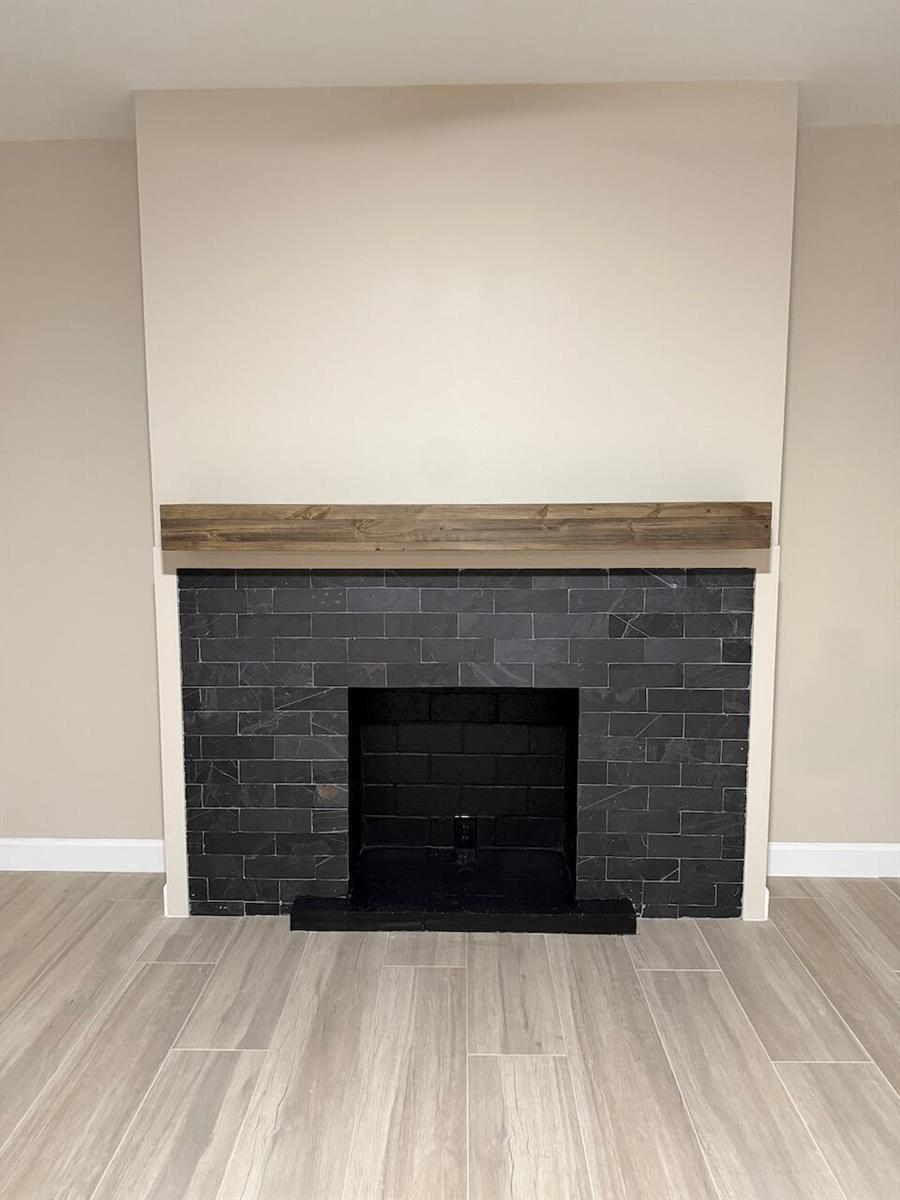 A fireplace with black stone tile, a wooden mantel, and a beige wall surround — 79 Lake Arbor Drive # 79, Palm Springs FL 33461, PALM SPRINGS, FL