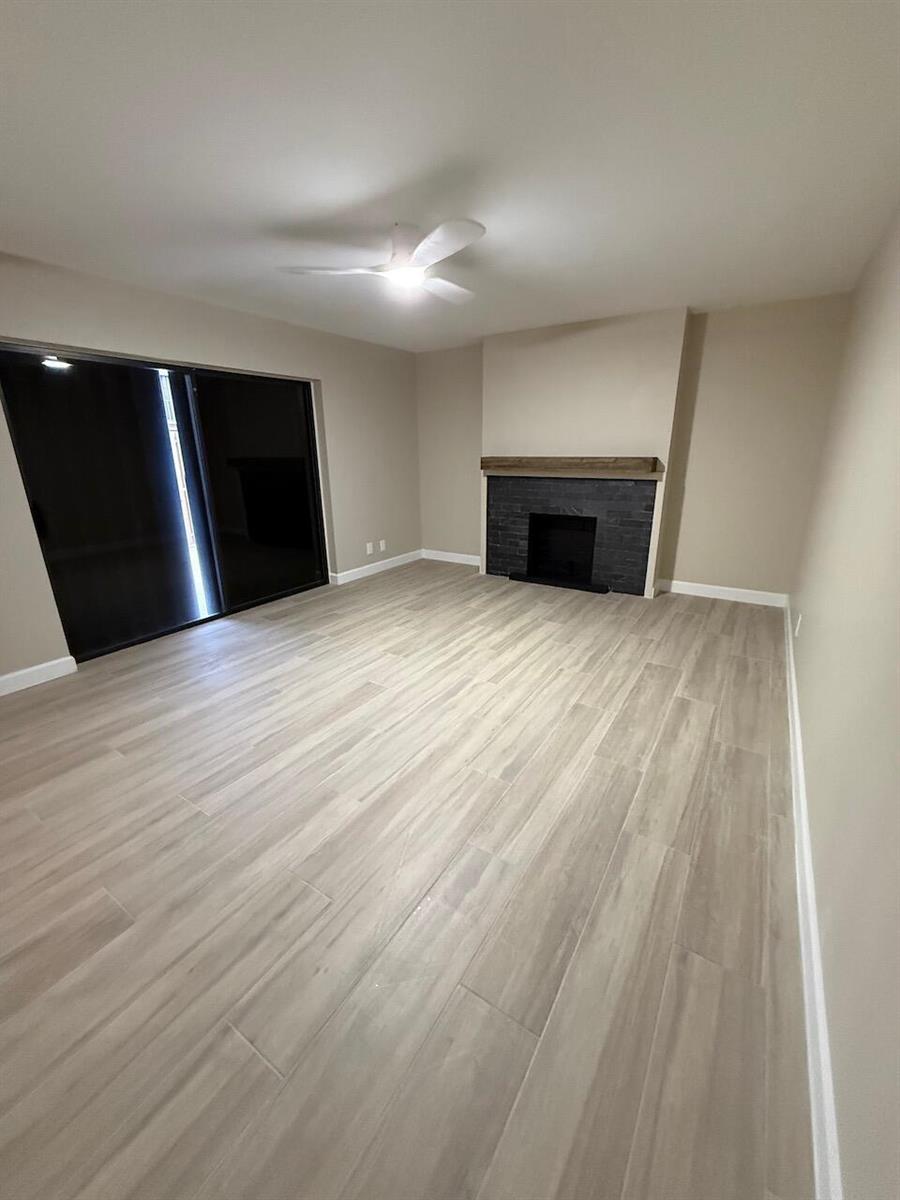 A living room features light wood-look tile flooring, a black fireplace, and sliding glass doors — 79 Lake Arbor Drive # 79, Palm Springs FL 33461, PALM SPRINGS, FL