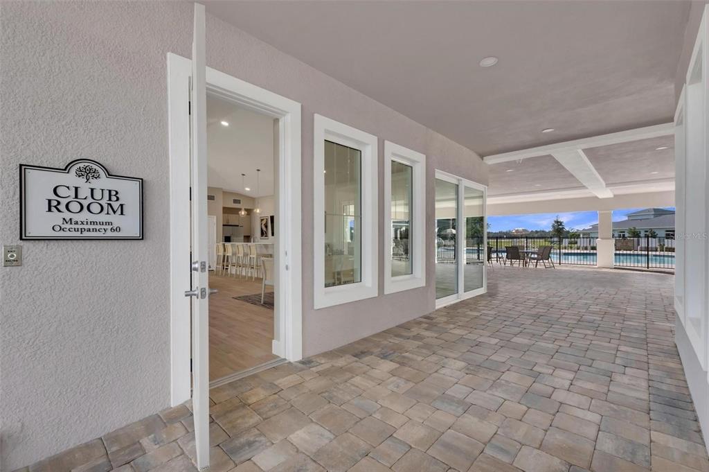A paved patio leads to a club room entrance with a maximum occupancy sign — 938 MEGANO BOULEVARD, DELAND, FL