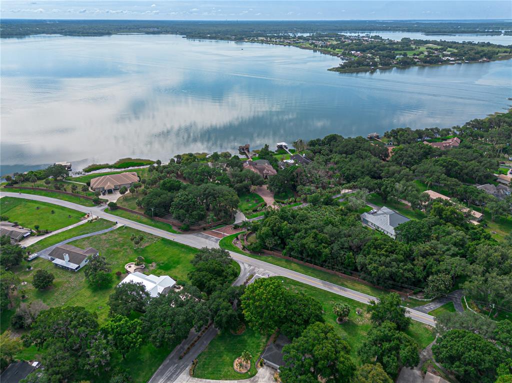 An aerial view shows houses nestled among trees along the shore of a large lake — 000 LAKESHORE POINTE BOULEVARD, MOUNT DORA, FL