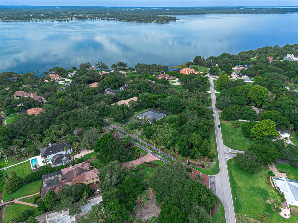 An aerial view shows a road winding through a wooded residential area near a lake — 000 LAKESHORE POINTE BOULEVARD, MOUNT DORA, FL