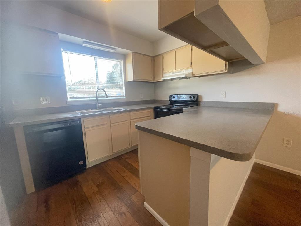 A kitchen features light-colored cabinets, a black dishwasher, a stove, and a gray countertop — 4419 S SEMORAN BOULEVARD UNIT 7, ORLANDO, FL