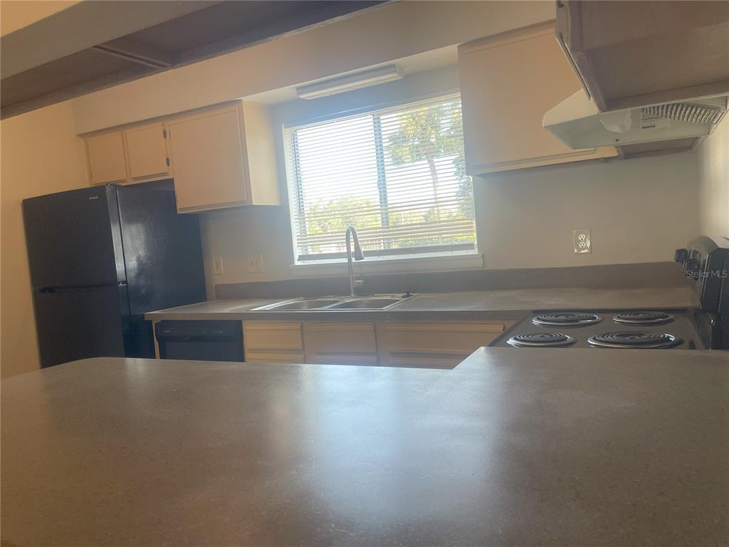 A kitchen features a black refrigerator, a double-basin sink, and a stove with coil burners — 4419 S SEMORAN BOULEVARD UNIT 7, ORLANDO, FL
