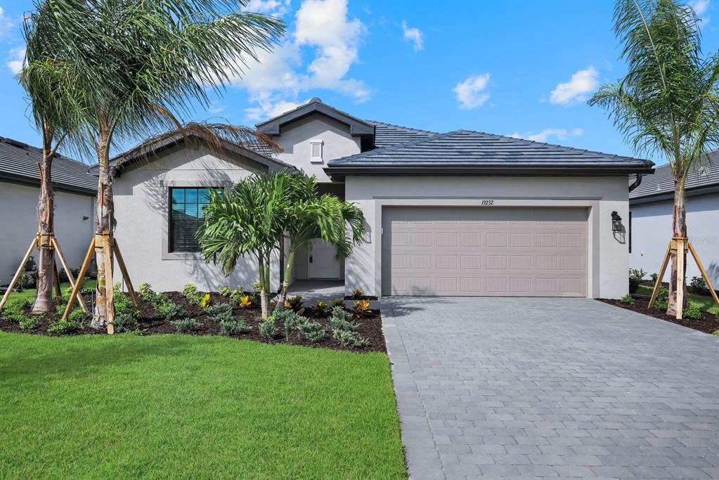 A single-story house with a gray tiled roof, stucco exterior, and a paved driveway — 19232 GENTRY PLACE, ESTERO, FL