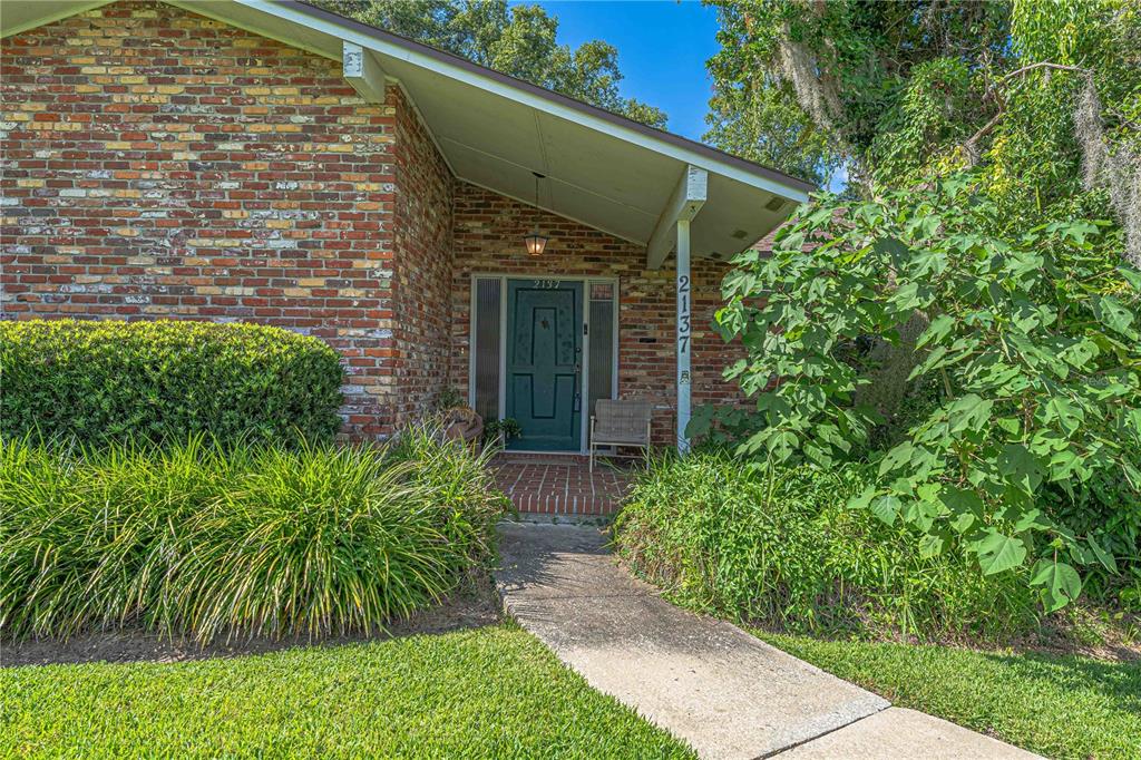 A brick house exterior features a covered entryway with a dark green front door — 2137 SE 11TH STREET, OCALA, FL