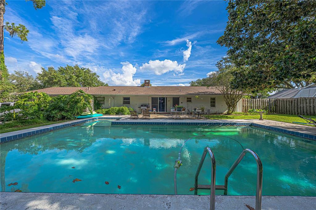 A backyard swimming pool sits in front of a single-story house with a patio — 2137 SE 11TH STREET, OCALA, FL