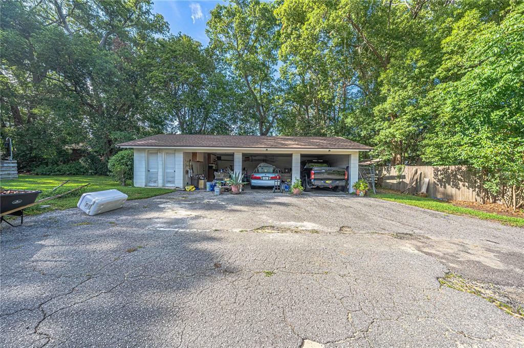 A detached three-car garage sits at the end of a cracked asphalt driveway — 2137 SE 11TH STREET, OCALA, FL