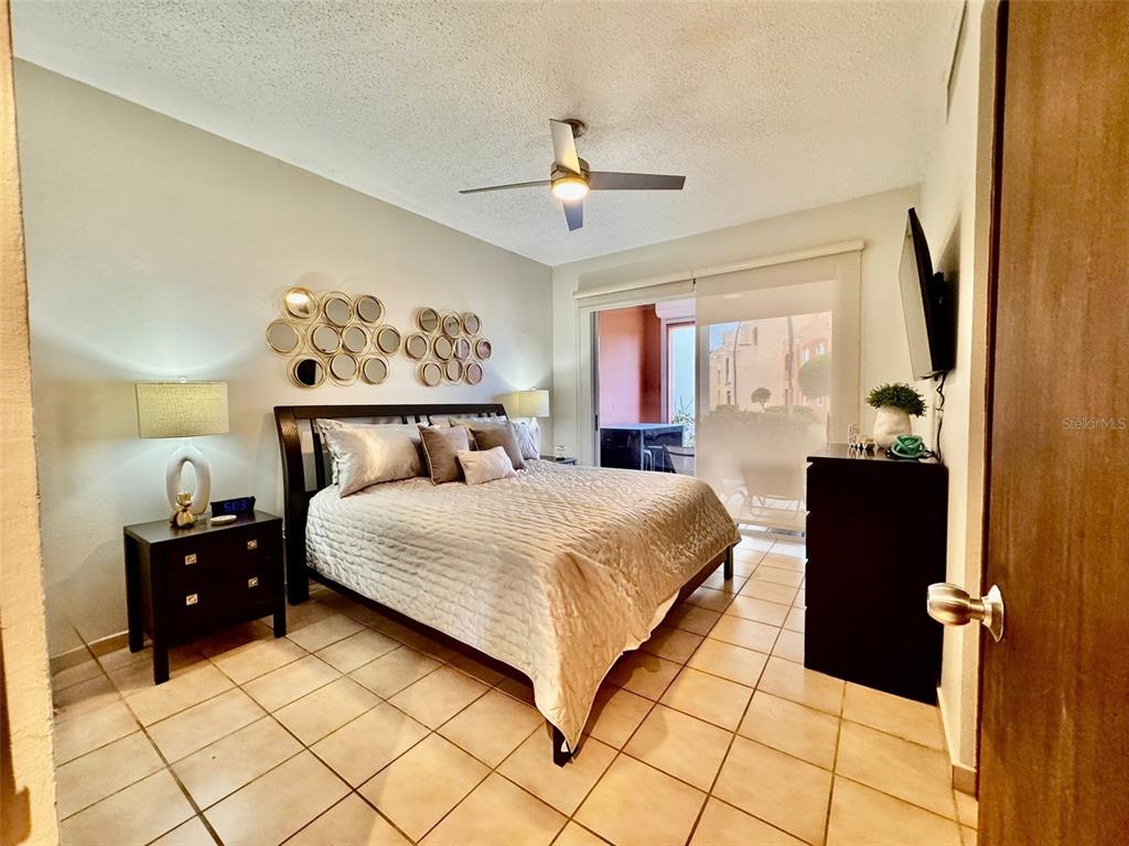 A bedroom features a bed, tiled floors, a ceiling fan, and a sliding glass door — Fairway Courts FAIRWAY COURTS UNIT 828, HUMACAO, PR