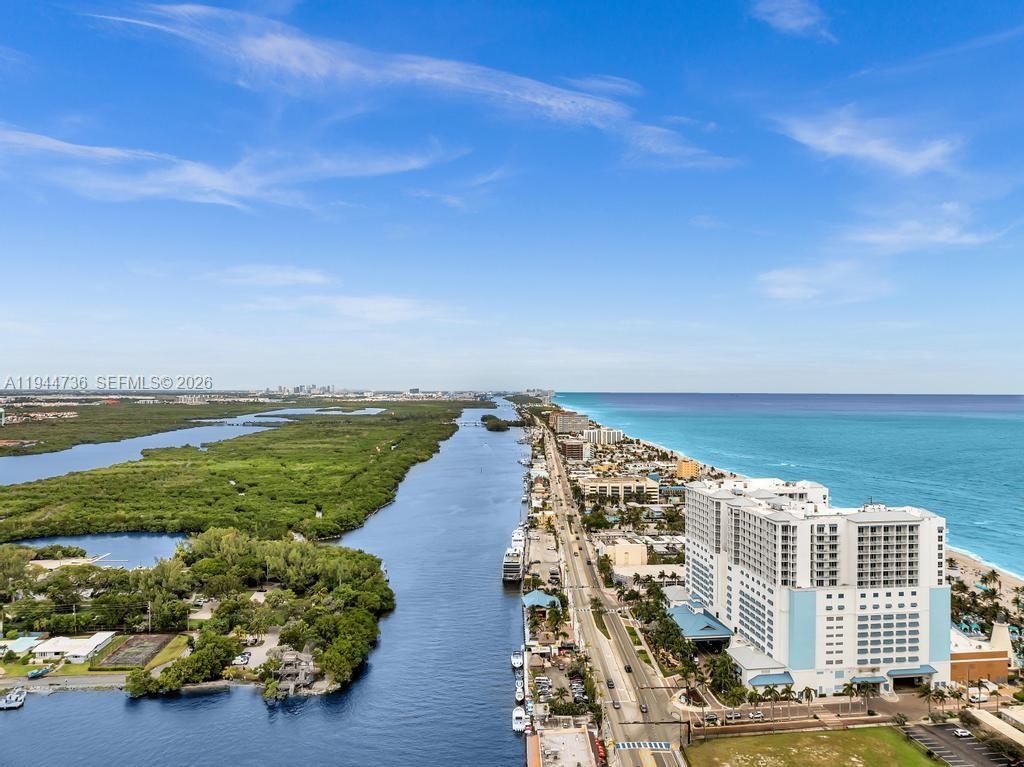 An aerial view shows a coastal landscape with a waterway, lush vegetation, and high-rise buildings — 1318 N Ocean Dr, Hollywood FL 33019, HOLLYWOOD, FL