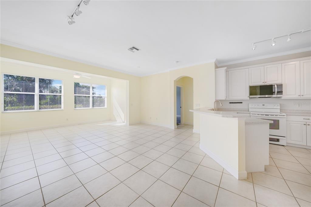 An open-concept kitchen and living area with white cabinets, tile flooring, and large windows — 3810 COBIA VILLAS COURT, PUNTA GORDA, FL
