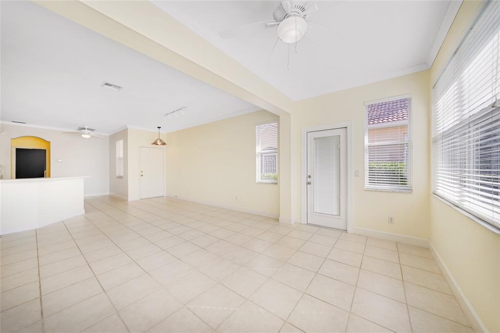 A bright, open-concept room features light-colored tile flooring, white walls, ceiling fans, and glass doors — 3810 COBIA VILLAS COURT, PUNTA GORDA, FL