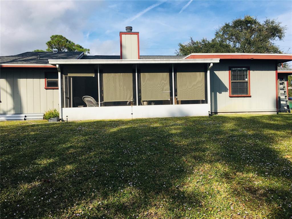 A rear view of a single-story house featuring a screened-in porch and a brick chimney — 7101 NORTH BOULEVARD, FORT PIERCE, FL