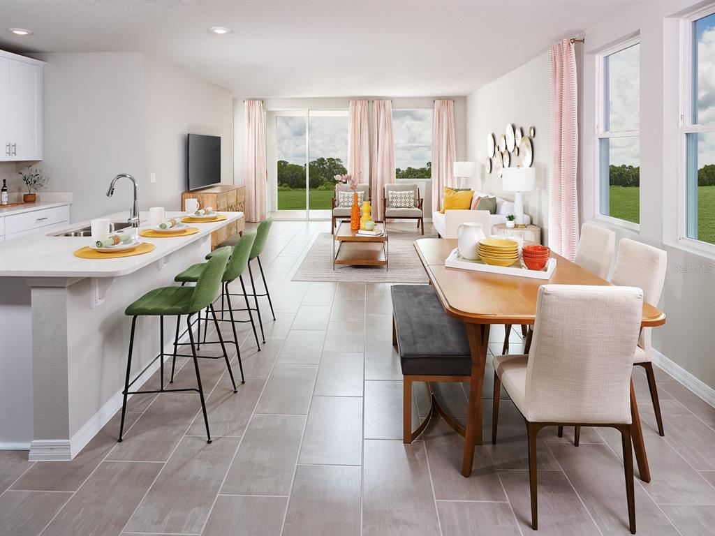 An open-concept kitchen, dining area, and living room with tile floors and large windows — 360 LAZY SHORE DRIVE, NOKOMIS, FL