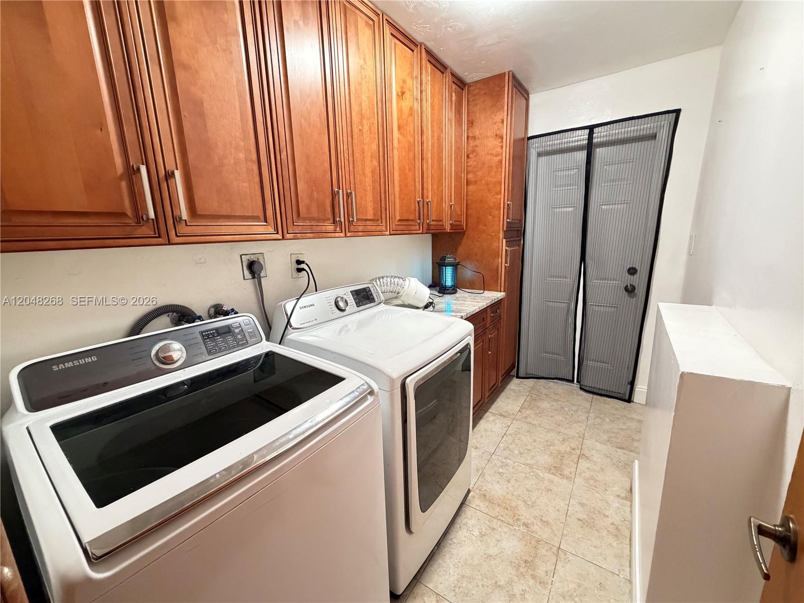 A laundry room features Samsung appliances, wood cabinets, and a mesh screen door — 45 SE 14th St, Dania Beach FL 33004, DANIA BEACH, FL