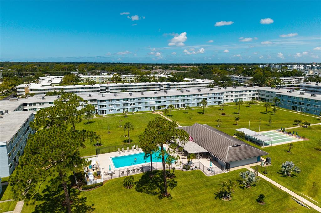 An aerial view shows a multi-story apartment complex with a swimming pool and clubhouse — 4715 BAY STREET NE UNIT 222, ST PETERSBURG, FL