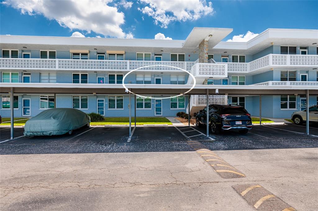 The exterior of a multi-story apartment building features a covered parking area and balconies — 4715 BAY STREET NE UNIT 222, ST PETERSBURG, FL