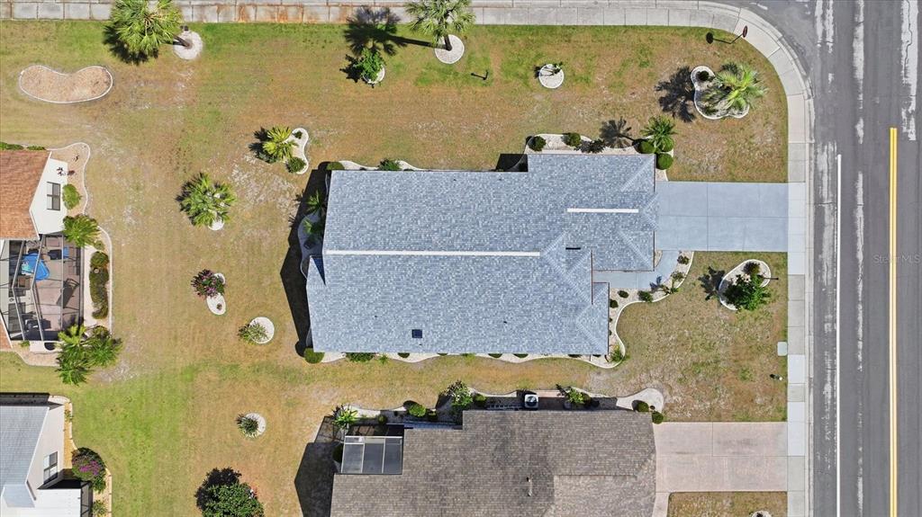 An aerial view shows a house with a gray roof, driveway, and landscaped yard — 1834 E DEL WEBB BOULEVARD, SUN CITY CENTER, FL