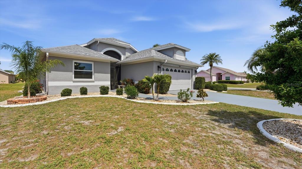 A single-story gray house with a two-car garage and a landscaped front yard — 1834 E DEL WEBB BOULEVARD, SUN CITY CENTER, FL