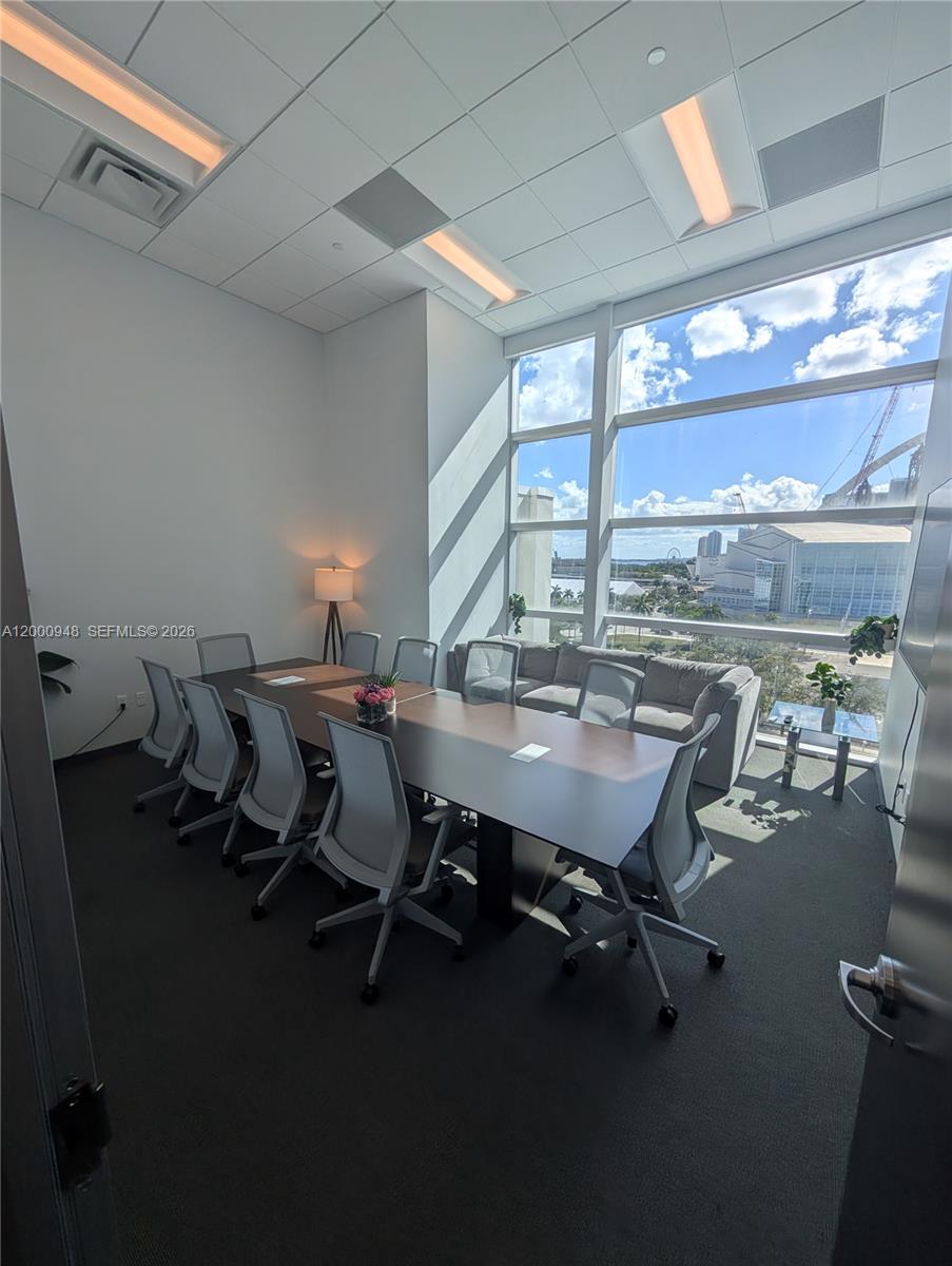 A modern conference room features a long table, ergonomic chairs, and floor-to-ceiling windows with city views — 1501 Biscayne Blvd # C1, Miami FL 33132, MIAMI, FL