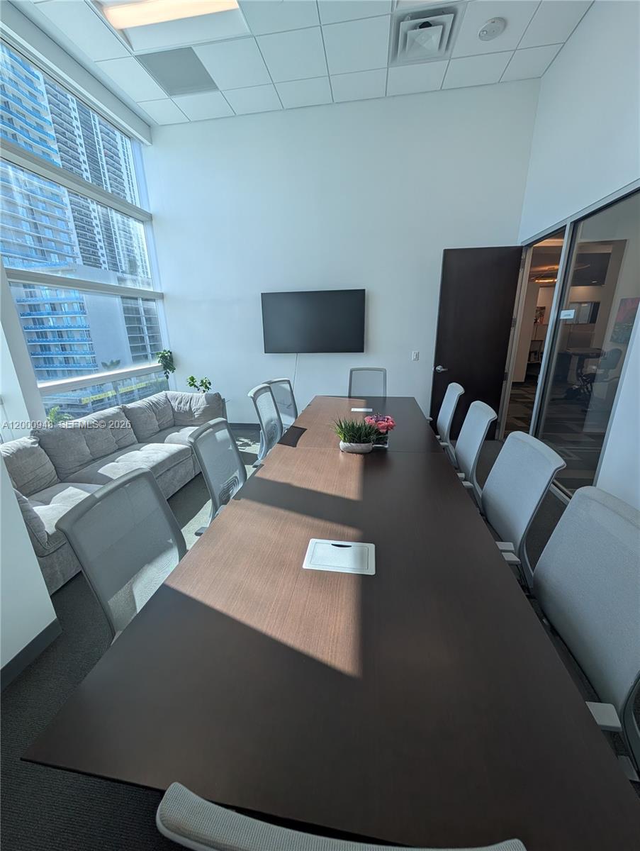 A conference room features a long dark table, gray chairs, a sofa, and floor-to-ceiling windows — 1501 Biscayne Blvd # C1, Miami FL 33132, MIAMI, FL