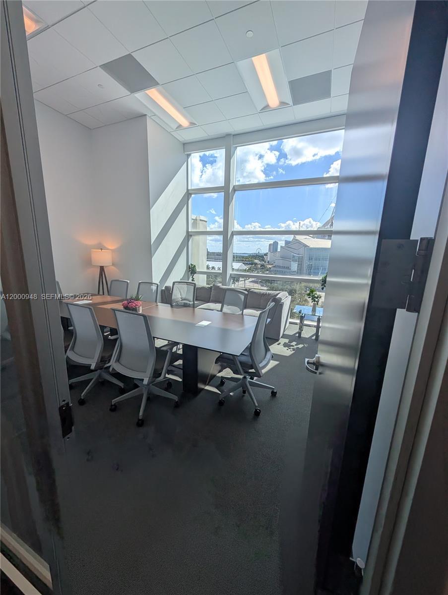 A modern conference room features a long table, ergonomic chairs, and floor-to-ceiling windows with city views — 1501 Biscayne Blvd # C1, Miami FL 33132, MIAMI, FL