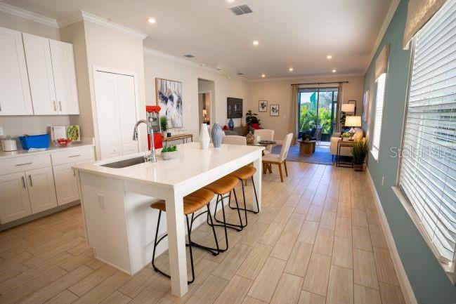 A kitchen with a white island and stools opens into a living area with tile floors — 3864 BLUETHREAD WAY, POINCIANA, FL