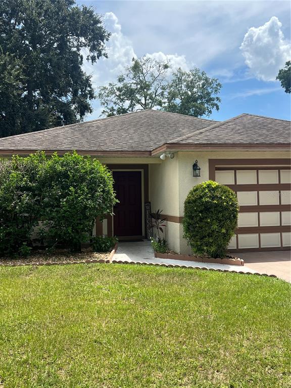 A single-story house with a tan stucco exterior, a brown roof, and a two-car garage — 4252 PAPPY KENNEDY STREET, ORLANDO, FL