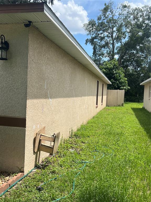 The exterior side of a stucco house features a hose reel and a security camera — 4252 PAPPY KENNEDY STREET, ORLANDO, FL