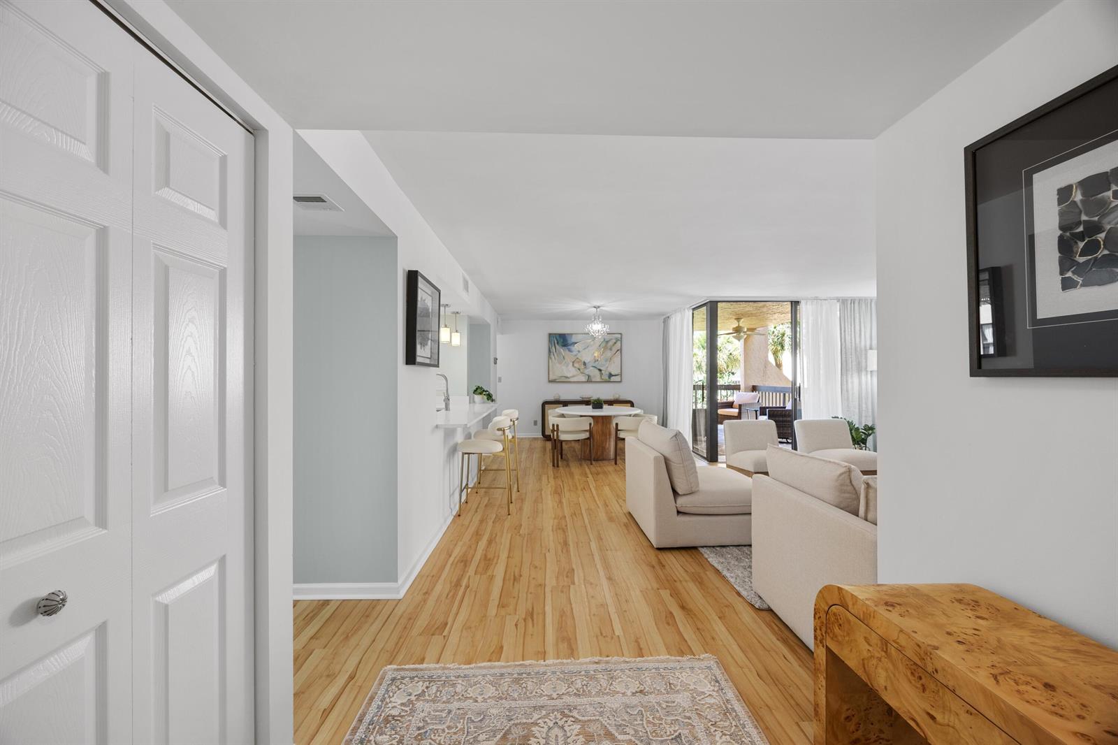 A view from a hallway into an open-concept living and dining area with light wood floors — 750 Egret Circle # 6210, Delray Beach FL 33444, DELRAY BEACH, FL