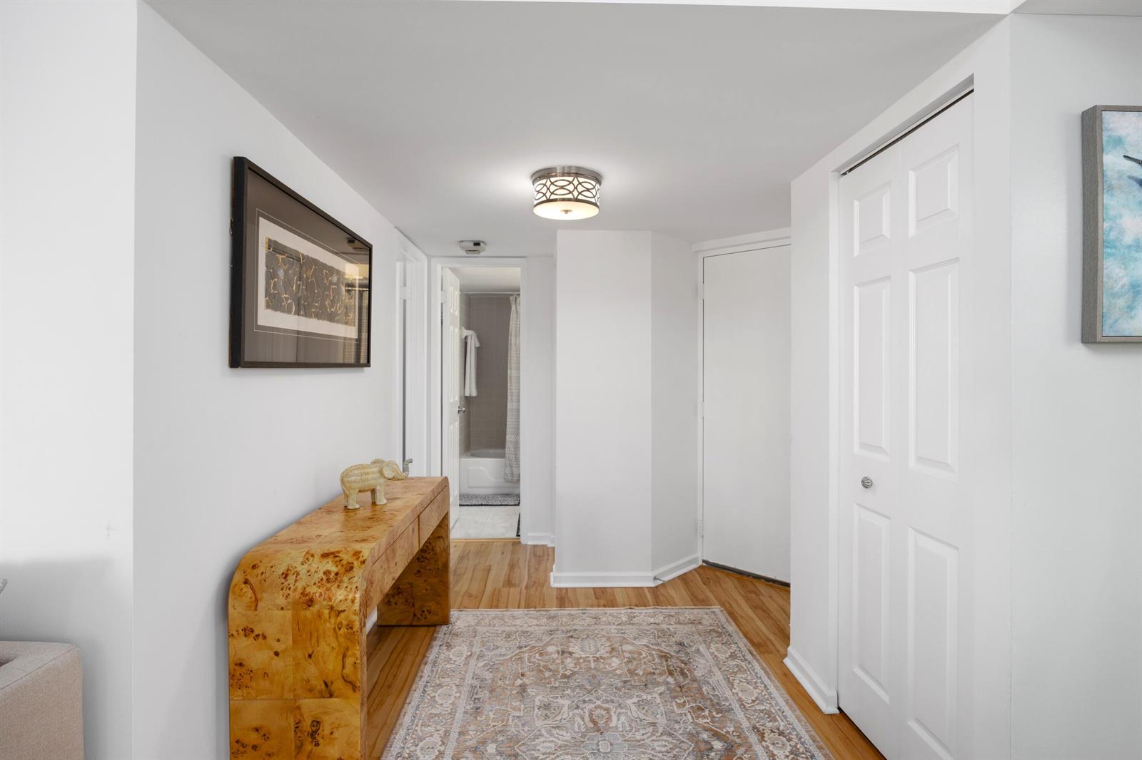 A hallway features a wooden console table, a patterned rug, and a bathroom doorway — 750 Egret Circle # 6210, Delray Beach FL 33444, DELRAY BEACH, FL