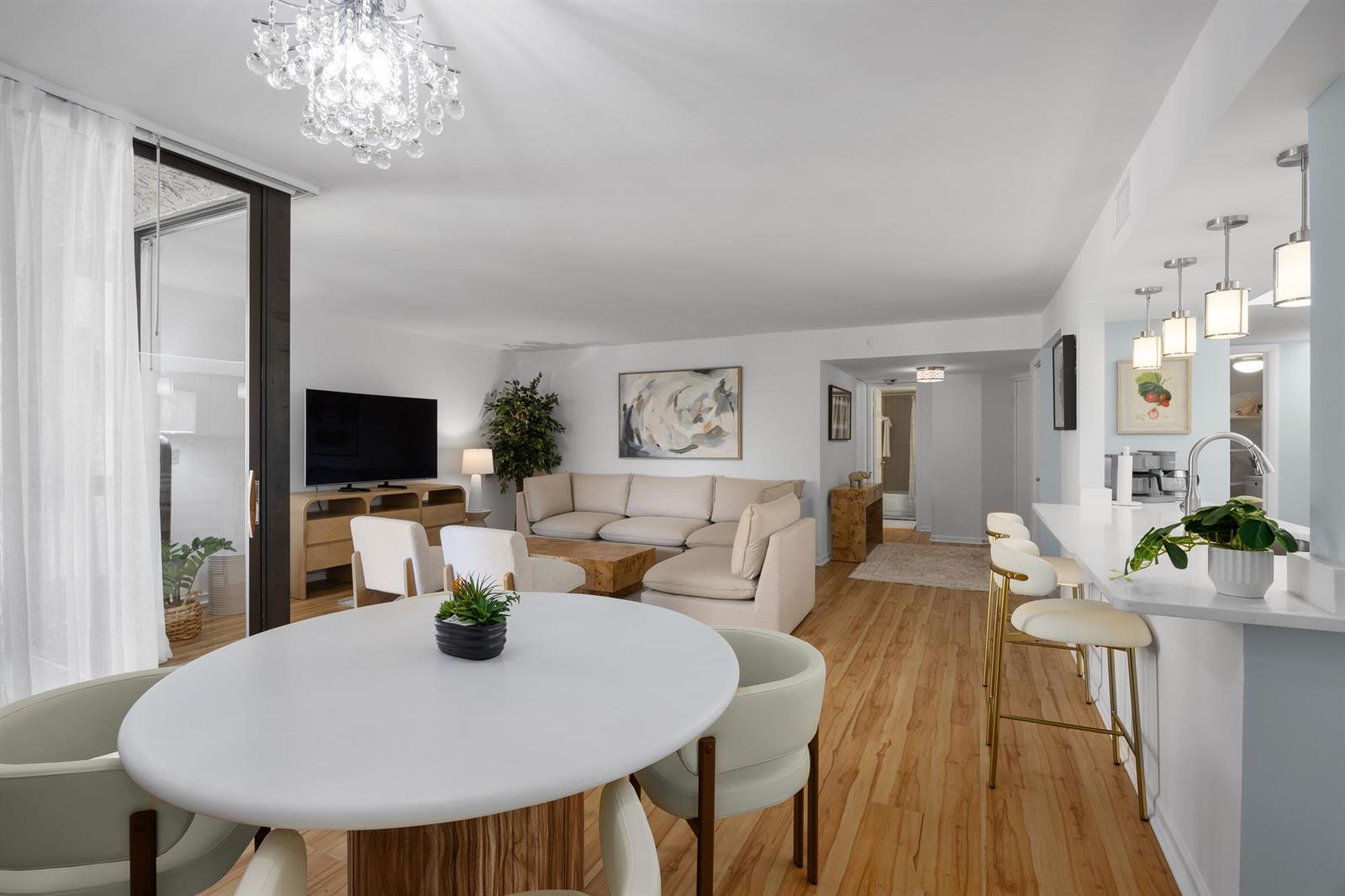 An open-concept living and dining area features light wood flooring, a sectional sofa, and chandelier — 750 Egret Circle # 6210, Delray Beach FL 33444, DELRAY BEACH, FL