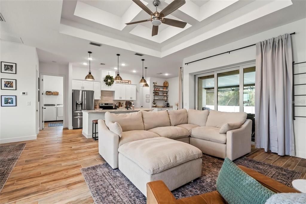 A bright kitchen features white cabinets, granite countertops, stainless steel appliances, and wood-look flooring — 8233 GIVLIC LANE, NORTH PORT, FL