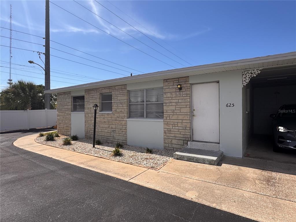 A single-story building exterior features light-colored stone veneer, a white door, and a gravel garden — 12400 PARK BOULEVARD UNIT 625, SEMINOLE, FL