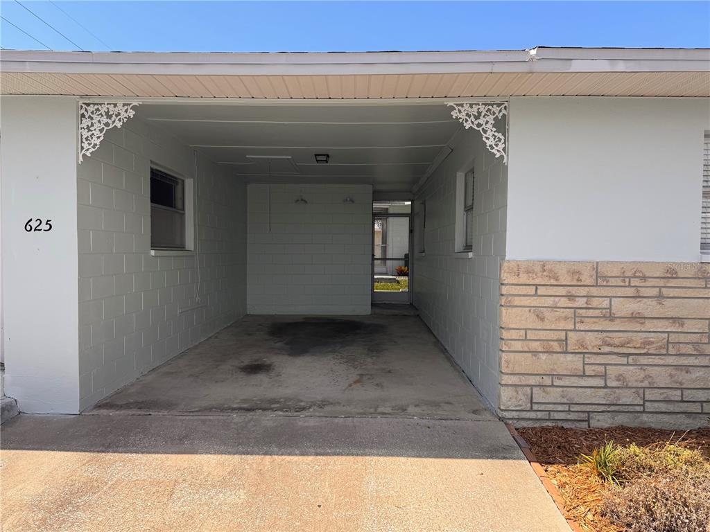 A concrete carport features white block walls, decorative corner brackets, and a rear screen door — 12400 PARK BOULEVARD UNIT 625, SEMINOLE, FL
